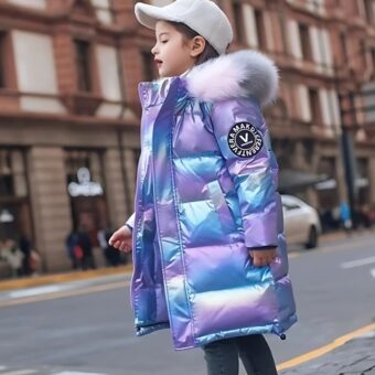 Jeune fille de profil debout dans la rue portant une casquette blanche, un jeans bleu et une doudoune chaude et brillante de couleur bleu style hologramme, longue jusqu'aux cuisses avec une fourrure en fourrure rose clair et grise.