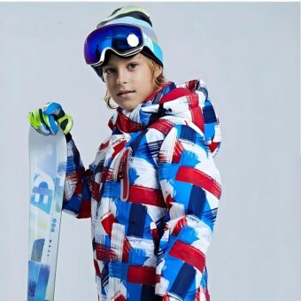 Doudoune de ski pour enfants portée par un enfant avec un casque de ski et des skis dans le gant droit.