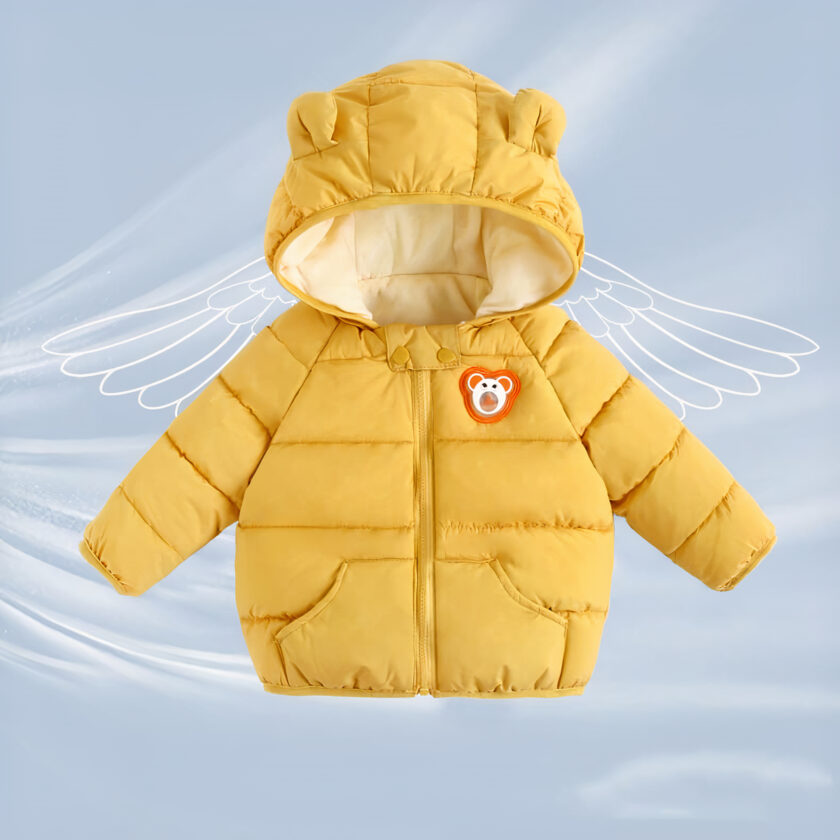 On voit une doudoune jaune moutarde sur fond bleu ciel. La doudoune est pour enfant, avec une capuche dotée de petites oreilles d'ourson. Elle a un logo ourson orange sur la poitrine.