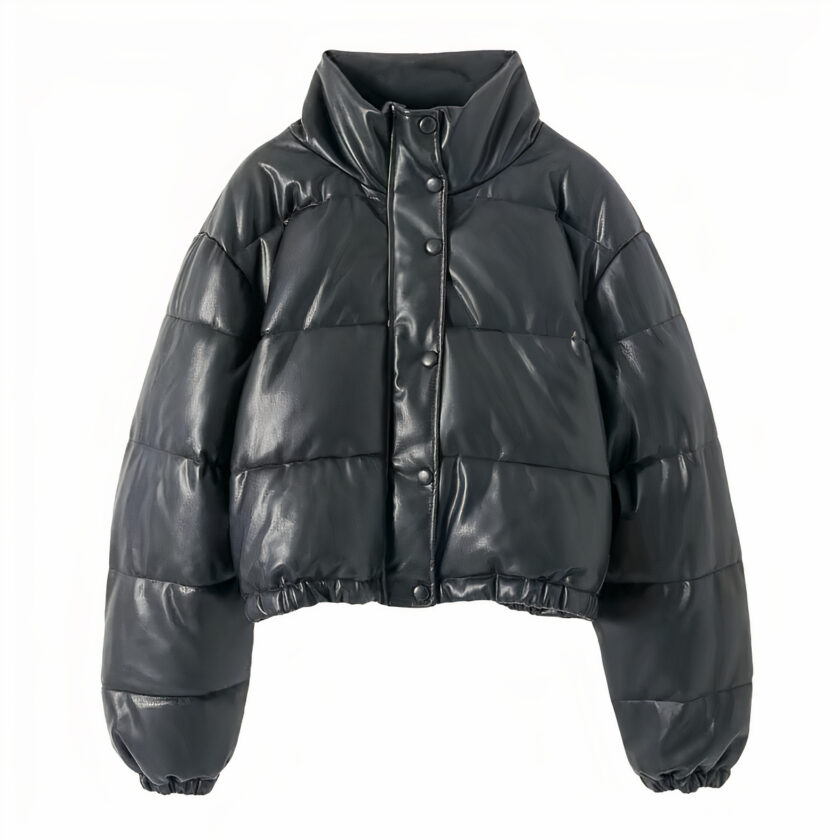 On voit une doudoune en similicuir noir, sur fond blanc. La coupe est très moderne, courte, crop-top. La doudoune est matelassée.