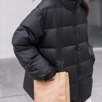 photo d'une femme portant une doudoune courte de couleur noir qui marche dans la rue