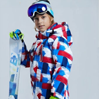 Doudoune de ski pour enfants porter par un enfant avec un casque de ski et des skis dans le gant droit.