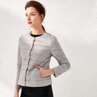 Femme portant une doudoune grise fine et un pantalon noir, fond blanc.