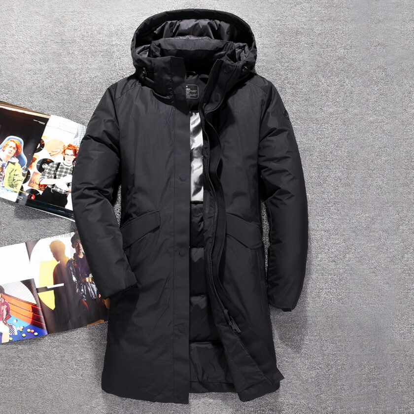 Doudoune longue et épaisse pour homme Doudoune noire longue et à capuche sur fond gris.