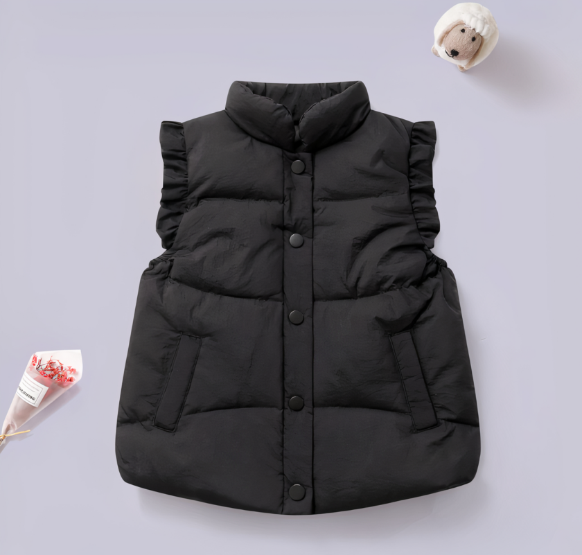 On voit une jolie doudoune noire sans manches pour petite fille. Elle est présentée sur un fond violet.