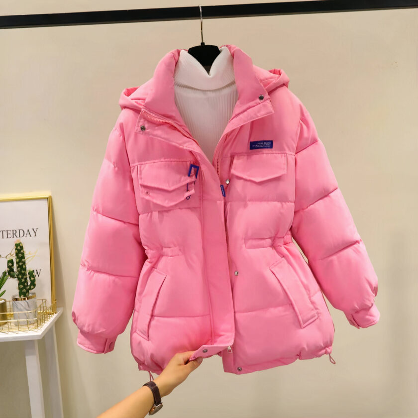 Doudoune rose sur un ceintre avec une main qui tient le bas de la doudoune.