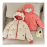 Doudoune réversible pour fille en version rose, disposée sur un canapé de couleur beige.