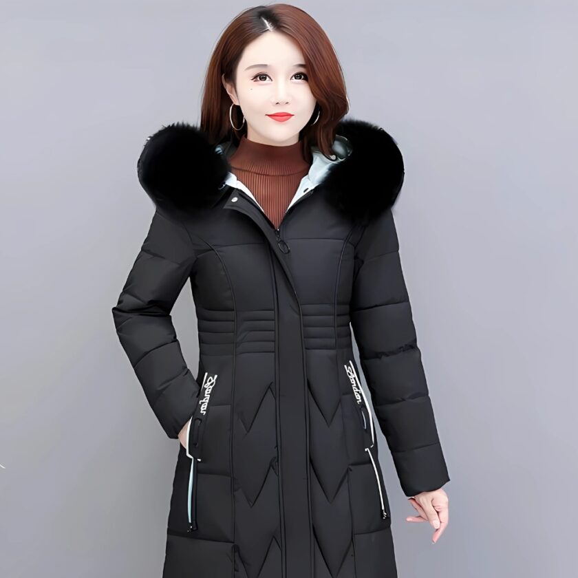 Femme asiatique aux cheveux mi_longs bruns portant une doudoune noire longue et matelassée cintrée avec de la fourrure noire sur la capuche. Elle tient sa main droite dans la poche de la doudoune. Sur fond gris.