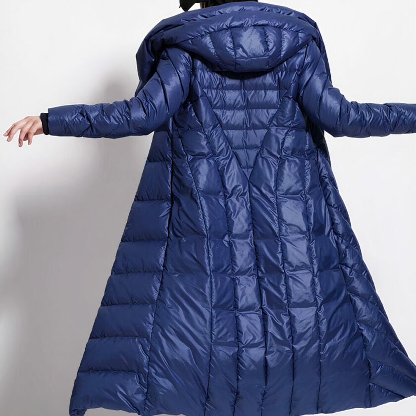 Longue doudoune imperméable bleu marine portée par une femme devant un fond gris.