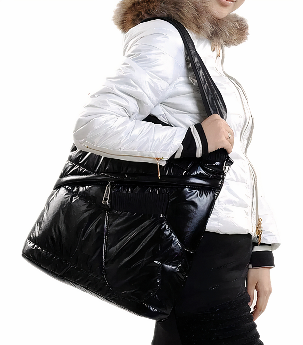 Femme de côté sans visage avec une doudoune blanche à fourrure marron qui porte un sac doudoune rectangulaire en vernis noir sur l'épaule.
