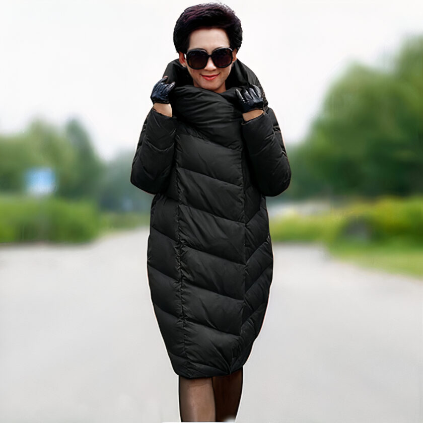 Femme âgée marchant sur un chemin de campagne et portant une doudoune cocon mi-longue noire.