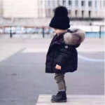Enfant dehors portant une doudoune noire pour enfants.