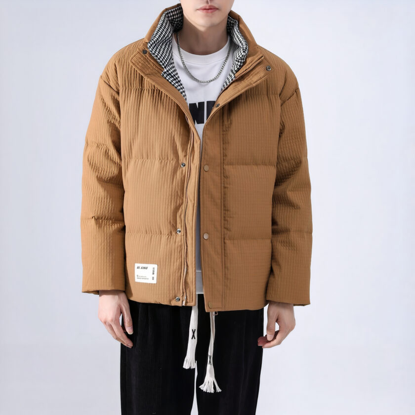 Homme blanc portant une doudoune beige et une pantalon noir sur un fond gris