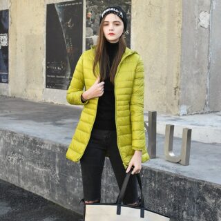 Femme dans la rue portant une doudoune jaune avec un bonnet et un sac à main beige