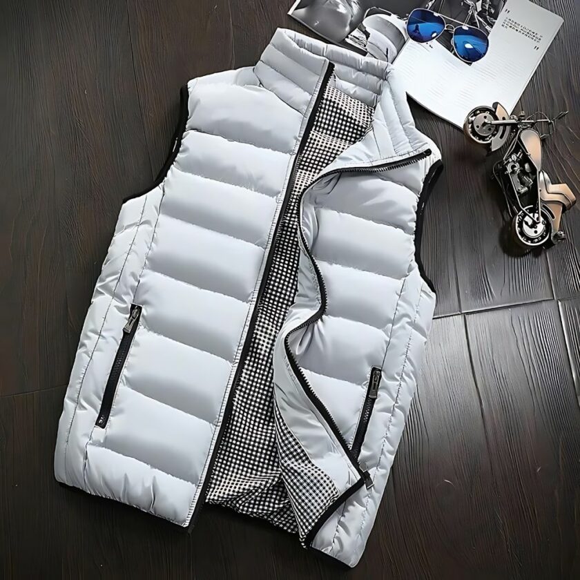 Doudoune homme sans manches slim fit grande taille couleur gris clair avec doublure intérieure motif Prince de Galles, zips contrastants, posée à plat sur un fond en bois sombre