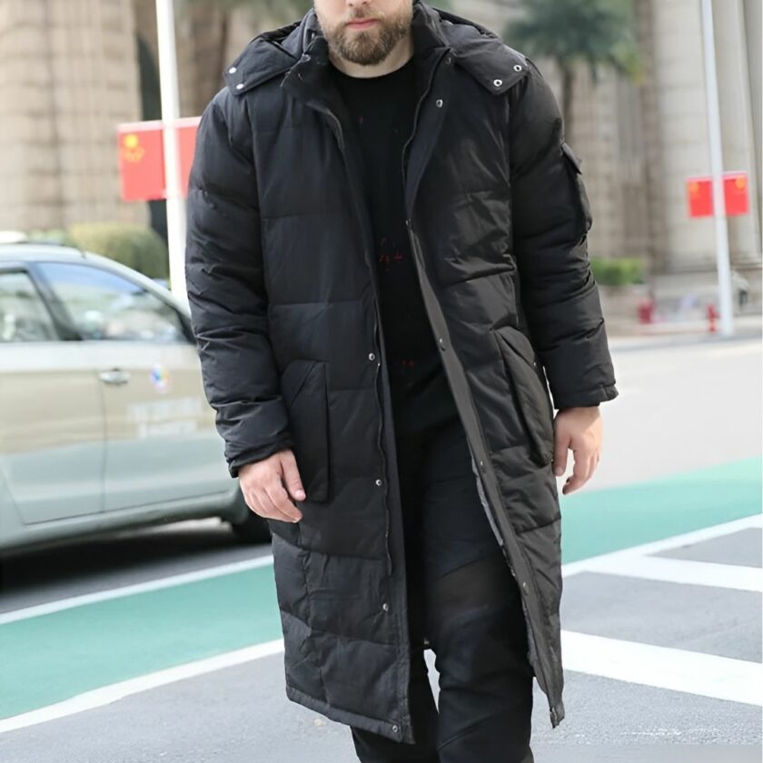Homme portant la doudoune longue grande taille pour homme dans une rue derrière une voiture beige qui passe.