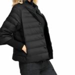 Une femme blonde tournée sur le droit, qui porte la courte doudoune à manches courtes pour femme noire,
