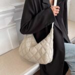 on voit une femme porter à l'épaule un sac doudoune demi-lune pour femme le sac est beige